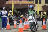 Seorang pengendara ojek daring bermanuver saat mengikuti kompetisi keselamatan berkendara atau safety riding di Mapolresta Samarinda, Kalimantan Timur, Kamis (26/6/2025). Kompetisi yang diselenggarakan dalam rangka memeriahkan HUT Ke-79 Bhayangkara itu diikuti puluhan ojek daring untuk menguji keterampilan berkendara aman dan kemampuan ketika berkendara yang efektif untuk peningkatan kesadaran atas prediksi bahaya di jalan raya. Antara Kaltim/M Risyal Hidayat