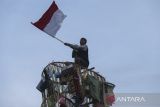 Warga mengibarkan bendera Merah Putih saat mengikuti lomba panjat pinang di Kelurahan Banjarnegara, Ciwandan, Kota Cilegon, Banten, Selasa (1/7/2025). Perlombaan tersebut digelar dalam rangka memperingati HUT ke-79 Bhayangkara yang pada tahun ini mengangkat tema Polri untuk Masyarakat. ANTARA FOTO/Angga Budhiyanto/gp
