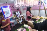 Pembeli melakukan pembayaran menggunakan Kode Respons Cepat Standar (QRIS) pada festival kuliner di GOR Segiri Samarinda, Kalimantan Timur, Selasa (1/7/2025). Menurut data dari Kantor Perwakilan Bank Indonesia (KPwBI) Kalimantan Timur, jumlah pengguna baru dan merchant QRIS di Kalimantan Timur terus mengalami peningkatan, pada triwulan I tahun 2025 jumlah pengguna QRIS tumbuh sebesar 8,21 persen (yoy), melambat dibandingkan dengan triwulan IV 2024 yang tumbuh 23,69 persen (yoy). Antara Kaltim/M Risyal Hidayat