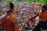 Masyarakat menyaksikan dua warga bergantian saling menyabet menggunakan rotan saat tradisi Ojung di Desa Nguter, Kecamatan Pasirian, Lumajang, Jawa Timur, Rabu (2/7/2025). Tradisi Ojung tersebut digelar rutin tiap setahun sekali saat selamatan desa yang biasanya diperingati saat bulan Suro pada penanggalan Jawa dalam rangka menjaga tradisi dan budaya setempat. Antara Jatim/Irfan Sumanjaya/um