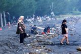 Wisatawan bermain di bibir Pantai yang banyak sampah di Pantai Pulau Santen, Banyuwangi, Jawa Timur, Rabu (2/7/2025). Sejak satu minggu terakhir ombak tinggi menyebabkan penumpukan sampah di bibir Pantai yang membuat para nelayan tidak melaut karena jaring mereka seiring robek akibat tersangkut sampah. Antara Jatim/Budi Candra Setya/um