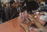 Pegawai Kantor Pos menghitung uang pencairan Bantuan Subsidi Upah (BSU) di Kantor Pos Kota Tasikmalaya, Jawa Barat, Jumat (4/7/2025). Pemerintah memberikan bantuan subsidi upah kepada 18.114 peneriman manfaat bagi pekerja di wilayah Kota dan Kabupaten Tasikmalaya sebesar Rp600 ribu. ANTARA FOTO/Adeng Bustomi/agr