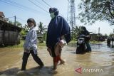 Warga melintasi banjir di Desa Gaga, Pakuhaji, Kabupaten Tangerang, Banten, Minggu (6/7/2025). Banjir dengan ketinggian 15 - 30 cm tersebut akibat meluapnya debit Sungai Cisadane yang dipicu air kiriman dari wilayah Bogor dan tingginya curah hujan pada Sabtu (5/7). ANTARA FOTO/Putra M. Akbar/gp