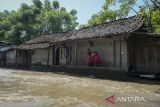 Warga melihat kondisi di depan rumahnya yang terendam banjir di Desa Gaga, Pakuhaji, Kabupaten Tangerang, Banten, Minggu (6/7/2025). Banjir dengan ketinggian 15 - 30 cm tersebut akibat meluapnya debit Sungai Cisadane yang dipicu air kiriman dari wilayah Bogor dan tingginya curah hujan pada Sabtu (5/7). ANTARA FOTO/Putra M. Akbar/gp