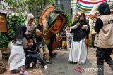 Petugas mengenakan kostum dinosaurus jenis Dilophosaurus menyapa pengunjung wahana Jurrasic Java di pusat perbelanjaan Paris Van Java, Bandung, Jawa Barat, Senin (7/7/2025). Pusat perbelanjaan tersebut menggelar wahana Jurassic Java yang menampilkan dua ekor 