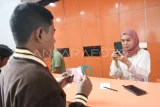 Petugas memotret bukti penerimaan Bantuan Subsidi Upah (BSU) 2025 tahap kedua di Kantor Pos Samarinda, Kalimantan Timur, Senin (7/7/2025). Berdasarkan data dari BPJS Ketenagakerjaan, jumlah penerima BSU tahap kedua tercatat sebanyak 4,5 juta pekerja atau buruh sebesar Rp600 ribu per orangnya. Antara Kaltim/M Risyal Hidayat/foc.