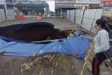 Seorang warga mengamati kondisi jalan yang amblas di jalur Denpasar-Gilimanuk, Desa Bajera, Tabanan, Bali, Selasa (8/7/2025). Jalur yang merupakan akses utama menuju ke Pulau Jawa tersebut sejak Senin (7/7) hingga saat ini ditutup akibat jalan amblas dengan kedalaman sekitar enam meter dan menyebabkan kemacetan lalu lintas. ANTARA FOTO/Nyoman Hendra Wibowo/wsj.