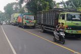 Warga mendorong sepeda motornya di dekat sejumlah truk yang terjebak macet akibat jalan amblas di jalur Denpasar-Gilimanuk, Desa Bajera, Tabanan, Bali, Selasa (8/7/2025).  Jalur yang merupakan akses utama menuju ke Pulau Jawa tersebut sejak Senin (7/7) hingga saat ini ditutup akibat jalan amblas dengan kedalaman sekitar enam meter dan menyebabkan kemacetan lalu lintas. ANTARA FOTO/Nyoman Hendra Wibowo/wsj.