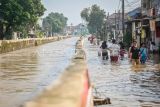 Warga melewati banjir di Perumahan Pondok Maharta, Pondok Aren, Tangerang Selatan, Banten, Selasa (8/7/2025). Banjir yang menggenangi permukiman warga tersebut disebabkan tingginya curah hujan serta sistem drainase yang buruk. ANTARA FOTO/Rivan Awal Lingga/tom.
