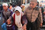Polisi menggandeng jamaah haji dari kelompok terbang (kloter) 97 berjalan menuju gedung Muzdalifah setibanya di Asrama Haji Sukolilo Surabaya, Surabaya, Jawa Timur, Jumat (11/7/2025). Pihak Panitia Penyelenggara Ibadah Haji (PPIH) Debarkasi Surabaya menerima kedatangan 322 haji yang merupakan kloter terakhir yang tiba di Surabaya usai menunaikan ibadah haji di Tanah Suci. Antara Jatim/Didik Suhartono/um