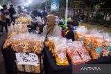 Pedagang menggunakan gawai sambil berjualan pada bazar kuliner gelaran Piala Presiden 2025 di Stadion Si Jalak Harupat, Kabupaten Bandung, Jawa Barat, Sabtu (12/7/2025). Ketua Steering Committe (SC) Piala Presiden 2025, Maruarar Sirait menyatakan sedikitnya terdapat 110 umkm berjualan di area stadion selama penyelenggaraan Piala Presiden tersebut untuk meningkatkan roda ekonomi para pelaku umkm dan masyarakat sekitar. ANTARA FOTO/Novrian Arbi/agr
