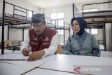 Menteri Sosial Saifullah Yusuf (kiri) didampingi istri Fatma Saifullah Yusuf (kanan) menulis testimoni saat kunjungan kerja di Sekolah Rakyat di kompleks Sentra Abiyoso Cimahi, Jawa Barat, Sabtu (12/7/2025). Dalam kunjungan tersebut Mensos berdialog dengan calon siswa, orang tua, dan guru serta meninjau kesiapan fasilitas, sarana dan pra sarana penunjang pembelajaran di sekolah rakyat yang akan beroperasi pada 14 Juli 2025. ANTARA FOTO/Abdan Syakura/agr