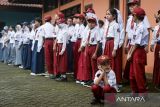 Seorang siswa penyandang tuna wicara jongkok saat melaksanakan upacara bendera di Sekolah Khusus YKDW 02, Kota Tangerang, Banten, Senin (14/7/2025). Pemerintah Provinsi Banten mencatat sebanyak 811 sekolah swasta telah bergabung dalam pelaksanaan program sekolah gratis dengan alokasi dana sebesar Rp159 miliar untuk enam bulan pertama guna pemerataan akses pendidikan di wilayah tersebut. ANTARA FOTO/Putra M. Akbar/gp