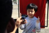 Seorang anak menjalani perekaman data untuk pembuatan Kartu Identitas Anak (KIA) melalui layanan jemput bola Disdukcapil Kota Pontianak di area Car Free Day (CFD) Pontianak, Kalimantan Barat, Minggu (13/7/2025). Dinas Kependudukan dan Pencatatan Sipil (Disdukcapil) Kota Pontianak membuka layanan perekaman Kartu Identitas Anak (KIA) di area CFD untuk mempermudah masyarakat mengurus dokumen kependudukan. ANTARA FOTO/Jessica Wuysang