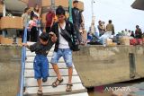 Seorang penumpang menuntun anaknya menuruni tangga dermaga menuju kapal cepat (speedboat) rute Pontianak–Sukadana di Pelabuhan Kapuas Indah, Pontianak, Kalimantan Barat, Senin (14/7/2025). Kapal cepat tersebut menjadi pilihan transportasi tercepat menuju Sukadana, Kabupaten Kayong Utara dengan waktu tempuh sekitar lima jam dan tarif Rp300 ribu per orang. ANTARA FOTO/Jessica Wuysang