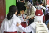 Orang tua memberikan uang jajan kepada anaknya saat hari pertama masuk sekolah di SDN 008 Samarinda, Kalimantan Timur, Senin (14/7/2025). Hari pertama masuk sekolah tahun ajaran 2025/2026 dimulai dengan masa pengenalan lingkungan sekolah (MPLS) untuk mengenalkan tenaga pendidik dan tata tertib kepada siswa baru. Antara Kaltim/M Risyal Hidayat/rwa. 