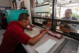 Petugas melayani warga yang mengurus dokumen kendaraan bermotornya di Samsat Surabaya Utara, Surabaya, Jawa Timur, Senin (14/7/2025). Pemprov Jawa Timur membuat kebijakan pembebasan pajak daerah bagi masyarakat Jawa Timur pemilik kendaraan bermotor roda dua dan roda tiga yang masuk dalam data Penyasaran Percepatan Penghapusan Kemiskinan Ekstrem (P3KE), beberapa di antaranya bebas sanksi administrasi keterlambatan Pajak Kendaraan Bermotor (PKB) dan Bea Balik Nama Kendaraan Bermotor (BBNKB), bebas PKB progresif serta bebas denda dan pokok tunggakan PKB tahun 2024 dan tahun sebelumnya, yang berlangsung sampai 31 Agustus 2025. Antara Jatim/Didik Suhartono/um