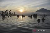 Pengunjung berenang di kolam renang air hangat alami saat menikmati sunrise Gunung Cikuray di Agrowisata Tepas Papandayan, Desa Karamatwangi, Kecamatan Cisurupan, Kabupaten Garut, Jawa Barat, Rabu (16/7/2025). Agrowisata Tepas Papandayan yang dibangun pada tahun 2019 oleh Pemerintah Desa dan dikelola Badan Usaha Milik Desa (BUMDes) Keramat Jaya itu mampu menghasilkan Pendapatan Asli Desa (PAD) sebesar Rp100 juta-Rp150 juta per tahun. ANTARA FOTO/Adeng Bustomi/agr