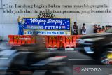 Maskot tim Persib Bandung berada di samping karangan bunga yang berisikan pesan selamat datang bagi pemain Persib Bandung yang baru di Jalan Asia Afrika, Bandung, Jawa Barat, Rabu (16/7/2025). Manajemen Tim Persib Bandung mengumumkan pemain asing baru ke-9 yaitu Frans Putros asal Irak melalui media karangan bunga di Jalan Asia Afrika setelah sebelumnya menggunakan media videotron, radio, koran, dan kartu pos. ANTARA FOTO/Raisan Al Farisi/agr