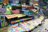 Sejumlah wisatawan mengunjungi Kampung Wisata Jodipan yang sedang dilakukan proses pengecatan ulang di Malang, Jawa Timur, Kamis (17/7/2025). Pengecatan ulang yang melibatkan warga setempat tersebut dilakukan untuk menyegarkan kembali tampilan kampung warna-warni yang menjadi ikon wisata Kota Malang, sebagai upaya mempertahankan daya tarik visual dan meningkatkan kunjungan wisatawan. Antara Jatim/Ari Bowo Sucipto/um
