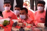 Sejumlah petugas kepolisian bersiaga di belakang beberapa tersangka yang dihadirkan dalam rilis ungkap kasus tindak pidana narkotika Polda Kalbar di Pontianak, Kalimantan Barat, Rabu (16/7/2025). Direktorat Reserse Narkoba Polda Kalbar merilis data pengungkapan 69 kasus tindak pidana narkoba periode Januari–awal Juli 2025, dengan jumlah tersangka 26 orang dan barang bukti berupa 23 kilogram sabu, 2.359 butir ekstasi, satu unit mobil, enam unit motor, serta sejumlah plat nomor palsu (plat merah dan plat hitam) yang ditemukan di dalam mobil salah satu tersangka. ANTARA FOTO/Jessica Wuysang