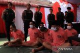 Sejumlah petugas kepolisian bersiaga di belakang beberapa tersangka yang dihadirkan dalam rilis ungkap kasus tindak pidana narkotika Polda Kalbar di Pontianak, Kalimantan Barat, Rabu (16/7/2025). Direktorat Reserse Narkoba Polda Kalbar merilis data pengungkapan 69 kasus tindak pidana narkoba periode Januari–awal Juli 2025, dengan jumlah tersangka 26 orang dan barang bukti berupa 23 kilogram sabu, 2.359 butir ekstasi, satu unit mobil, enam unit motor, serta sejumlah plat nomor palsu (plat merah dan plat hitam) yang ditemukan di dalam mobil salah satu tersangka. ANTARA FOTO/Jessica Wuysang