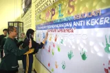 Kepala sekolah Margono (kiri) mendampingi siswa penyandang disabilitas menempelkan tangannya yang telah dilumuri cat air saat mengikuti deklarasi anti perundungan dan kekerasan dalam pelaksanaan Masa Pengenalan Lingkungan Sekolah (MPLS) di SLB Negeri Samarinda, Kalimantan Timur, Rabu (16/7/2025). Deklarasi tersebut bertujuan untuk menciptakan sekolah yang ramah anak yang terhindar dari perundungan, kekerasan serta dapat belajar dengan aman dan nyaman sehingga terbentuk anak yang berkarakter, bermartabat, dan bermanfaat. Antara Kaltim/M Risyal Hidayat/YU