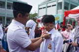 Wali Kota Balikpapan Rahmad Mas'ud (kiri) memakaikan seragam kepada siswa sekolah menengah pertama saat pembagian bantuan seragam sekolah gratis di SMP Negeri 27 Balikpapan, Kalimantan Timur, Rabu (16/7/2025). Pemkot Balikpapan membagikan bantuan 92 ribu stel seragam sekolah secara gratis kepada siswa baru jenjang TK, SD, dan SMP Tahun Ajaran 2025/2026 yang terdiri dari seragam nasional, pramuka, dan batik dengan anggaran mencapai Rp28 miliar yang bersumber dari APBD Kota Balikpapan. Antara Kaltim/Aditya Nugroho/YU/mrh