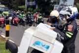 Polisi menilang pengendara yang melanggar lalu lintas saat Operasi Patuh Lodaya 2025 di Simpang PDAM, Cibinong, Kabupaten Bogor, Jawa Barat, Selasa (15/7/2025). Polres Bogor menggelar Operasi Patuh Lodaya 2025 selama dua pekan mulai 14-27 Juli 2025, operasi itu dilaksanakan dengan dua metode penindakan, yaitu tilang manual dan sistem Electronic Traffic Law Enforcement (ETLE) dengan sasaran tujuh pelanggaran diantaranya tidak memakai helm, melawan arus serta pengendara dibawah umur. ANTARA FOTO/Yulius Satria Wijaya/bar 