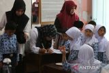 Petugas Pusat Kesehatan Masyarakat (Puskesmas) mendata nama nama murid saat  Cek Kesehatan Gratis (CKG) di sekolah Madrasyah Ibtidaiyah Negeri 6 Banda Aceh, Aceh, Rabu (23/7/2025). Pemerintah  meluncurkan program  Cek Kesehatan Gratis (CKG) bagi siswa usia 7-17 tahun yang akan dilaksanakan secara serentak  di seluruh  sekolah, SD, SMP,SMA dan Madrasyah hingga pesantren pada  Agustus 2025 dengan target  sebanyak 53,8 juta pelajar di 282.000 sekolah dari berbagai jenjang pendidikan. ANTARA FOTO/Ampelsa.