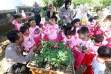 Kapolsek Plemahan AKP Bowo Wicaksono (kiri) membagikan bibit tanaman pepaya kepada anak-anak TK di Polsek Plemahan, Kabupaten Kediri, Jawa Timur, Rabu (23/7/2025). Kegiatan kunjungan anak TK di kantor polisi yang diisi dengan memberi makan ikan, menanam sayuran, dan pembagian bibit tanaman buah tersebut merupakan Program Polisi Sahabat Anak sebagai upaya edukasi ketahanan pangan tingkat rumah tangga kepada anak usia dini. ANTARA Jatim/Prasetia Fauzani/mas.