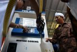 Petugas menata beras premium kemasan di samping mesin pompa minyak goreng Koperasi Kelurahan Merah Putih di Kelurahan Curug Mekar, Kota Bogor, Jawa Barat, Rabu (23/7/2025). Koperasi Kelurahan Merah Putih tersebut menyediakan barang kebutuhan pokok dan berinovasi menjual minyak goreng curah seharga Rp15.500 per liter menggunakan pom minyak goreng curah berkapasitas 150 liter. ANTARA FOTO/Arif Firmansyah/rwa. 