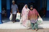 Warga berjalan keluar sambil menenteng masing-masing dua karung beras isi 10 kg program Bantuan Pangan Beras (BPB) periode Juni-Juli 2025 di Desa Srikaton Tulungagung, Jawa Timur, Sabtu (26/7/2025). Jumlah penerima bantuan pangan beras di Tulungagung tahun ini tercatat sebanyak 80.875 KPM (keluarga penerima manfaat), turun dibandingkan tahun lalu yang berjumlah 90.427 KPM. ANTARA Jatim/Destyan Sujarwoko/mas.