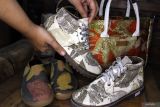Perajin Cecilia Triputri Wardhani menata sepatu ecoprint buatannya di rumah produksi Trilogi Ecoprint, Pandanwangi, Malang, Jawa Timur, Selasa (29/7/2025). Perajin tersebut berinovasi dengan memanfaatkan keanekaragaman hayati tanaman lokal seperti daun jati dan waru sebagai motif ciri khas serta mengembangkan kerajinan tas dari limbah plastik dengan mengusung konsep berkelanjutan (sustainable), sederhana dan siap pakai yang kemudian dipasarkan lewat media sosial hingga menembus pasar Australia, Portugal, dan berbagai kota di Indonesia, dengan harga Rp75 ribu hingga Rp400 ribu menurut jenis produk. Antara Jatim/Ari Bowo Sucipto/um