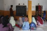 Sejumlah murid mengikuti kegiatan belajar mengajar tanpa meja dan kursi di Madrasah Diniyah Takmiliyah Awaliyah (MDTA) Hidayatul Mubtadiâin, Pulosari, Kabupaten Pandeglang, Banten, Rabu (30/7/2025). Pihak madrasah mengatakan lembaga pendidikan yang berlokasi di kaki Gunung Pulosari tersebut hingga kini belum dilengkapi dengan fasilitas meja dan kursi sejak didirikan pada tahun 2007 sehingga mengganggu aktivitas belajar mengajar di madrasah yang saat ini memiliki total murid sebanyak 70 orang dari seluruh tingkat dengan tenaga pengajar sebanyak enam orang itu. ANTARA FOTO/Angga Budhiyanto/gp