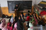 Sejumlah murid mengikuti kegiatan belajar mengajar tanpa meja dan kursi di Madrasah Diniyah Takmiliyah Awaliyah (MDTA) Hidayatul Mubtadiin, Pulosari, Kabupaten Pandeglang, Banten, Rabu (30/7/2025). Pihak madrasah mengatakan lembaga pendidikan yang berlokasi di kaki Gunung Pulosari tersebut hingga kini belum dilengkapi dengan fasilitas meja dan kursi sejak didirikan pada tahun 2007 sehingga mengganggu aktivitas belajar mengajar di madrasah yang saat ini memiliki total murid sebanyak 70 orang dari seluruh tingkat dengan tenaga pengajar sebanyak enam orang itu. ANTARA FOTO/Angga Budhiyanto/gp