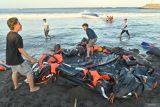 Warga berusaha menarik barang-barang dari kapal cepat Bali Dolphin Cruise 2 yang mengalami kecelakaan ke tepi pantai di kawasan Sanur, Denpasar, Bali, Selasa (5/8/2025). Kapal wisata yang mengangkut 75 penumpang dan lima awak kapal dari Pelabuhan Nusa Penida itu tenggelam dan kandas di alur masuk Pelabuhan Sanur yang mengakibatkan dua orang penumpang warga negara China meninggal dunia serta satu orang awak kapal masih dalam proses pencarian. ANTARA FOTO/Fikri Yusuf/wsj.