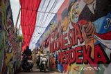 Pengendara sepeda motor melintas di bawah dekorasi kain merah putih di Kampung Rancabali, Padalarang, Kabupaten Bandung Barat, Jawa Barat, Kamis (7/8/2025). Warga setempat bergotong royong memasang kain merah putih sepanjang 100 meter dan membuat mural pahlawan nasional yang bertujuan untuk meningkatkan semangat nasionalisme serta menyemarakkan peringatan HUT Ke-80 Republik Indonesia. ANTARA FOTO/Abdan Syakura/agr
