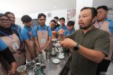 Instruktur Rizky Rahman (kedua kanan) menjelaskan kepada peserta tentang cara meracik kopi saat pelatihan barista di Surabaya, Jawa Timur, Kamis (7/8/2025). Pemerintah Kota Surabaya melalui Dinas Perindustrian dan Tenaga Kerja Kota Surabaya bekerjasama dengan Lembaga Pelatihan Kerja (LPK) Pesona Bintang Bangsa mengadakan pelatihan barista secara gratis tentang cara meracik berbagai jenis minuman kopi dan berbagai jenis minuman mocktail (nonalkohol) sebagai upaya untuk memberikan keterampilan kepada peserta yang dapat bermanfaat di dunia kerja atau untuk berwirausaha. ANTARA Jatim/Didik Suhartono/mas.
