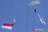 Prajurit TNI melakukan terjun payung dengan membawa bendera Merah Putih usai Upacara Gelar Pasukan Operasional dan Kehormatan Militer di Lapangan Udara (Lanud) Suparlan Pusdiklatpassus, Batujajar, Kabupaten Bandung Barat, Jawa Barat, Minggu (10/8/2025). Atraksi militer dan demonstrasi terpadu tersebut merupakan salah satu bentuk komitmen untuk memperkuat pertahanan negara dengan mengutamakan kemandirian, keunggulan operasional, dan teknologi pertahanan serta kesiapsiagaan. ANTARA FOTO/Abdan Syakura/agr