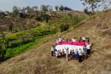 Sejumlah anak membentangkan bendera Merah Putih saat mengikuti kegiatan Sapa Desa Sobat Sosial di Pinggir, Nganjuk, Jawa Timur, Minggu (10/8/2025). Aksi membentangkan bendera Merah Putih di salah satu daerah pelosok di Nganjuk tersebut dipelopori oleh pemuda setempat sebagai upaya untuk menanamkan semangat kemerdekaan dan cinta tanah air kepada masyarakat khususnya anak-anak di desa itu. ANTARA Jatim/Muhammad Mada/mas.