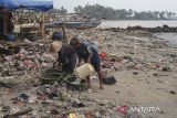 Nelayan memindahkan ikan hasil tangkapan ke dalam ember di sekitar tumpukan sampah di kawasan pesisir Desa Teluk, Labuan, Kabupaten Pandeglang, Banten, Senin (11/8/2025). Kementerian Kelautan dan Perikanan (KKP) mengupayakan untuk mengurangi volume sampah ke lautan melalui intervensi langsung di kawasan sungai, pesisir dan pulau kecil, serta pelabuhan dan wilayah aktivitas laut dengan menargetkan 70 persen sampah dapat dicegah masuk ke laut pada tahun 2029. ANTARA FOTO/Angga Budhiyanto/gp