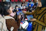 Guru membagikan buku rekening kepada siswa secara gratis dalam rangkaian kegiatan peringatan Hari Indonesia Menabung yang digelar Otoritas Jasa Keuangan (OJK) Kediri di Tulungagung, Jawa Timur, Senin (11/8/2025). Dalam kegiatan itu, OJK membagikan 450 buku rekening ssecara gratis kepada 450 siswa jenjang SD, SMP hingga SMA sebagia bagian dari edukasi literasi keuangan kepada siswa untuk belajar menabung sejak dini. ANTARA Jatim/Destyan Sujarwoko/mas.