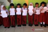 Sejumlah pelajar memegang dokumen kependudukan saat menunggu giliran perekaman data oleh petugas Disdukcapil Kota Pontianak di Sekolah Dasar Negeri (SDN) 10 Pontianak Utara, Kalimantan Barat, Selasa (20/5/2025). Sebanyak 118.557 anak atau 63,45 persen dari total anak di Kota Pontianak telah memiliki Kartu Identitas Anak (KIA) melalui program Pelayanan Cetak Kartu Identitas Anak Sehari Jadi (PECI HAJI) yang menyasar anak usia sekolah dengan sistem jemput bola di sekolah maupun di ruang publik. ANTARA FOTO/Jessica Wuysang