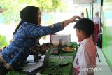 Petugas Disdukcapil Kota Pontianak menata rambut pelajar SD saat perekaman data untuk pembuatan Kartu Identitas Anak (KIA) dalam layanan jemput bola di Sekolah Dasar Negeri (SDN) 10 Pontianak Utara, Kalimantan Barat, Selasa (20/5/2025). Sebanyak 118.557 anak atau 63,45 persen dari total anak di Kota Pontianak telah memiliki Kartu Identitas Anak (KIA) melalui program Pelayanan Cetak Kartu Identitas Anak Sehari Jadi (PECI HAJI) yang menyasar anak usia sekolah dengan sistem jemput bola di sekolah maupun di ruang publik. ANTARA FOTO/Jessica Wuysang