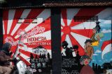 Warga melintas didekat lukisan mural bertema kemerdekaan dan kepahlawanan karya mahasiswa di kawasan Bendogerit, Kota Blitar, Jawa Timur, Selasa (12/8/2025). Selain untuk mengakomodir kreasi serta seni dalam rangka memeriahkan HUT RI ke 80, aksi melukis mural yang dilakukan oleh sejumlah mahasiswa dari Universitas Islam Balitar (UNISBA) tersebut juga bertujuan untuk mengkampanyekan nasionalisme serta semangat perjuangan para pahlawan kepada masyarakat. Antara Jatim/Irfan Anshori/um