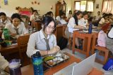 Pelajar menyantap makanan bergizi gratis di SMK Negeri 2 Denpasar, Bali, Rabu (13/8/2025). Pemerintah menargetkan capaian penerima program Makan Bergizi Gratis (MBG) sebanyak 20 juta orang sebelum HUT Ke-80 RI. ANTARA FOTO/Fikri Yusuf/wsj.