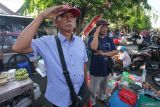Warga melakukan penghormatan saat upacara di pasar di Jalan Karang Menjangan, Surabaya, Jawa Timur, Minggu (17/8/2025). Upacara pengibaran bendera Merah Putih dalam rangka memperingati HUT ke-80 Kemerdekaan RI tersebut diikuti warga dan pedagang pasar. Antara Jatim/Didik Suhartono/um