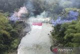 Foto udara warga membentangkan bendera Merah Putih raksasa di jembatan gantung Sukamenak, Kampung Benteng, Kecamatan Purbaratu, Kota Tasikmalaya, Jawa Barat, Minggu (17/8/2025). Pembentangan bendera merah putih sepanjang 150 persegi di Sungai Citanduy tersebut digelar oleh warga untuk menumbuhkan jiwa nasionalisme di kalangan anak muda serta mempererat tali silahturahmi antara warga Kabupaten Ciamis dengan Kota Tasikmalaya dalam rangka HUT Ke-80 Republik Indonesia. ANTARA FOTO/Adeng Bustomi/agr