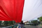 elajar SMA Negeri 1 Surabaya membentangkan Bendera Merah Putih di jalan Walikota Mustajab, Surabaya, Jawa Timur, Minggu (17/8/2025). Aksi pembentangan bendera Merah Putih dengan total panjang 14.905 meter secara serentak oleh 10.868 pelajar SMA dan SMK tersebut tercatat dalam Museum Rekor Dunia Indonesia (MURI) untuk kategori pembentangan rangkaian kain merah putih dengan pelajar terbanyak. ANTARA Jatim/Moch Asim.